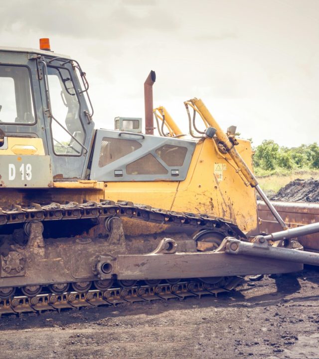 A powerful bulldozer on muddy construction ground under a cloudy sky.